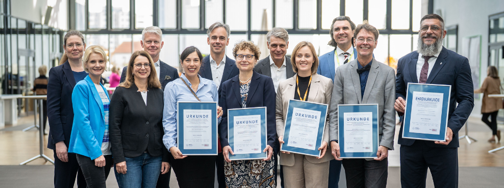 Gruppenfoto von Menschen, die Urkunden in die Kamera halten
