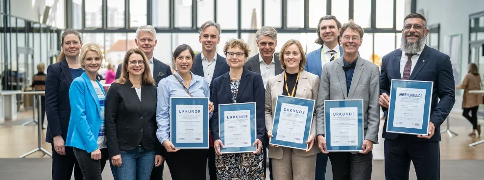 Gruppenfoto von Menschen, die Urkunden in die Kamera halten
