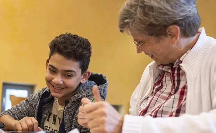 A young man, a teenager and a woman sit together at the table