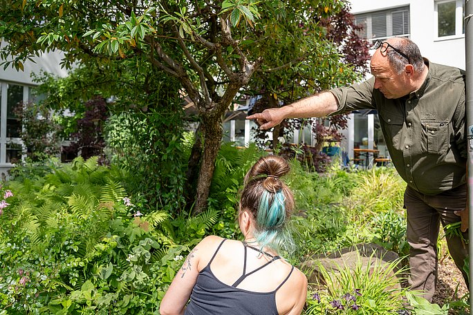 Eine Person zeigt auf etwas Besonderes im Garten