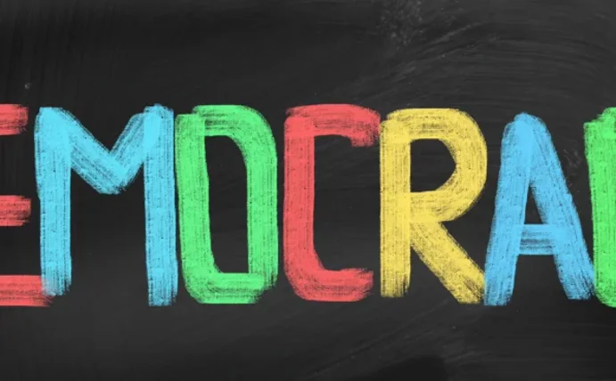 Man sieht einen bunten Schriftzug "Democracy".