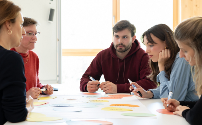 Research data management is to be anchored in the UW/H's Doctoral Programme in Nursing Science. (Photo: UW/H | Michael Schwettmann) Five people sit at a table and write keywords on colourful cards.