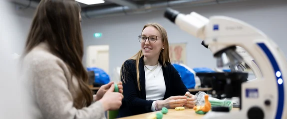 Zwei Studentinnen am Tisch mit Mikroskop