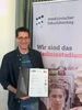 Dr Till Bachmann, anaesthetist from the Helios University Hospital Wuppertal at UW/H, has completed his Master of Medical Education (MME). A man with a certificate in his hand smiles at the camera.