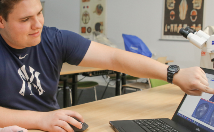 Zwei Studenten sitzen an einem Laptop.