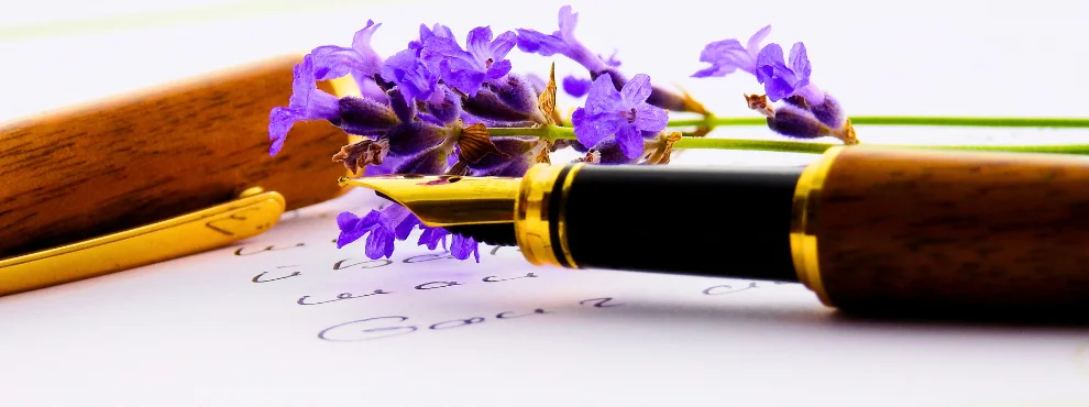 You can see a fine fountain pen against a white background with a purple flower. 