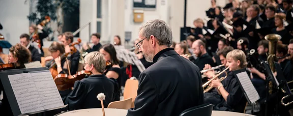 The UW/H orchestra (Photo: UW/H │ Daniela Arndt) A timpani player is in focus. In the background is the rest of the orchestra with string instruments.