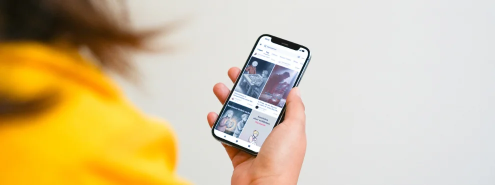 The image shows a woman from behind, with the focus on the smartphone she is holding. 