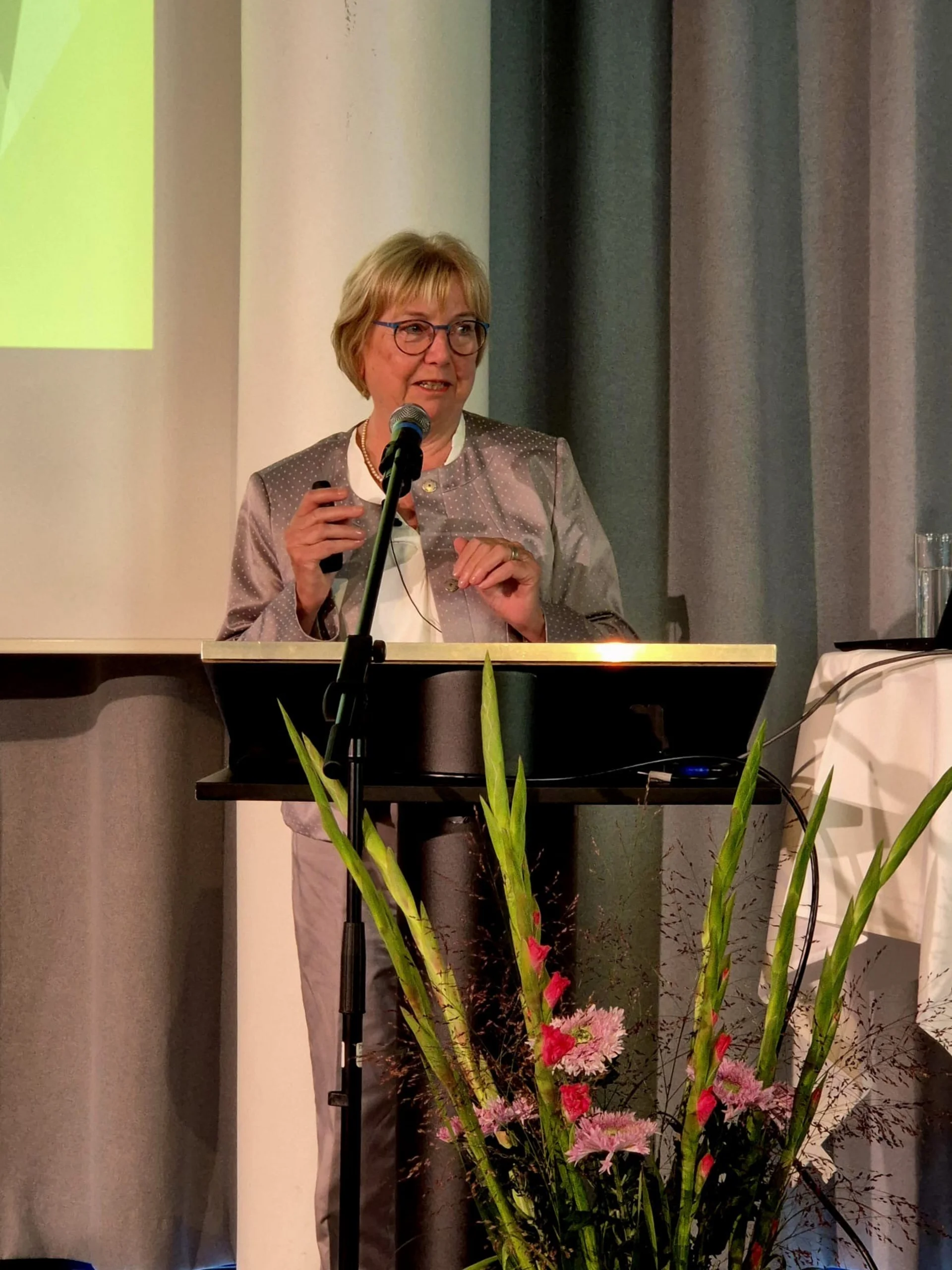 Christel Bienstein (Foto: Kristin Schütz) Christel Bienstein steht vor einem Podium und hält einen Vortrag