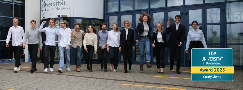 Laughing students in front of the main entrance of the university.