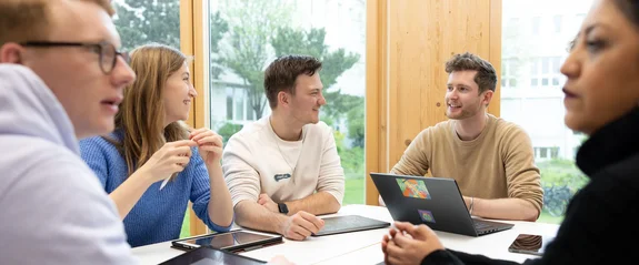 Five students sit around a table