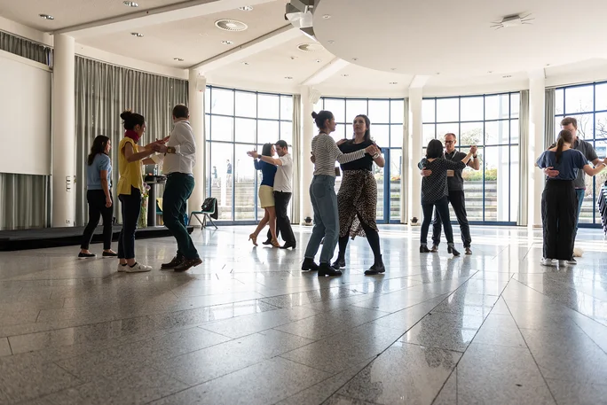 Dance workshop at the alumni reunion (Photo: UW/H | Florian Danner) Several couples are dancing in a room with a large window front.