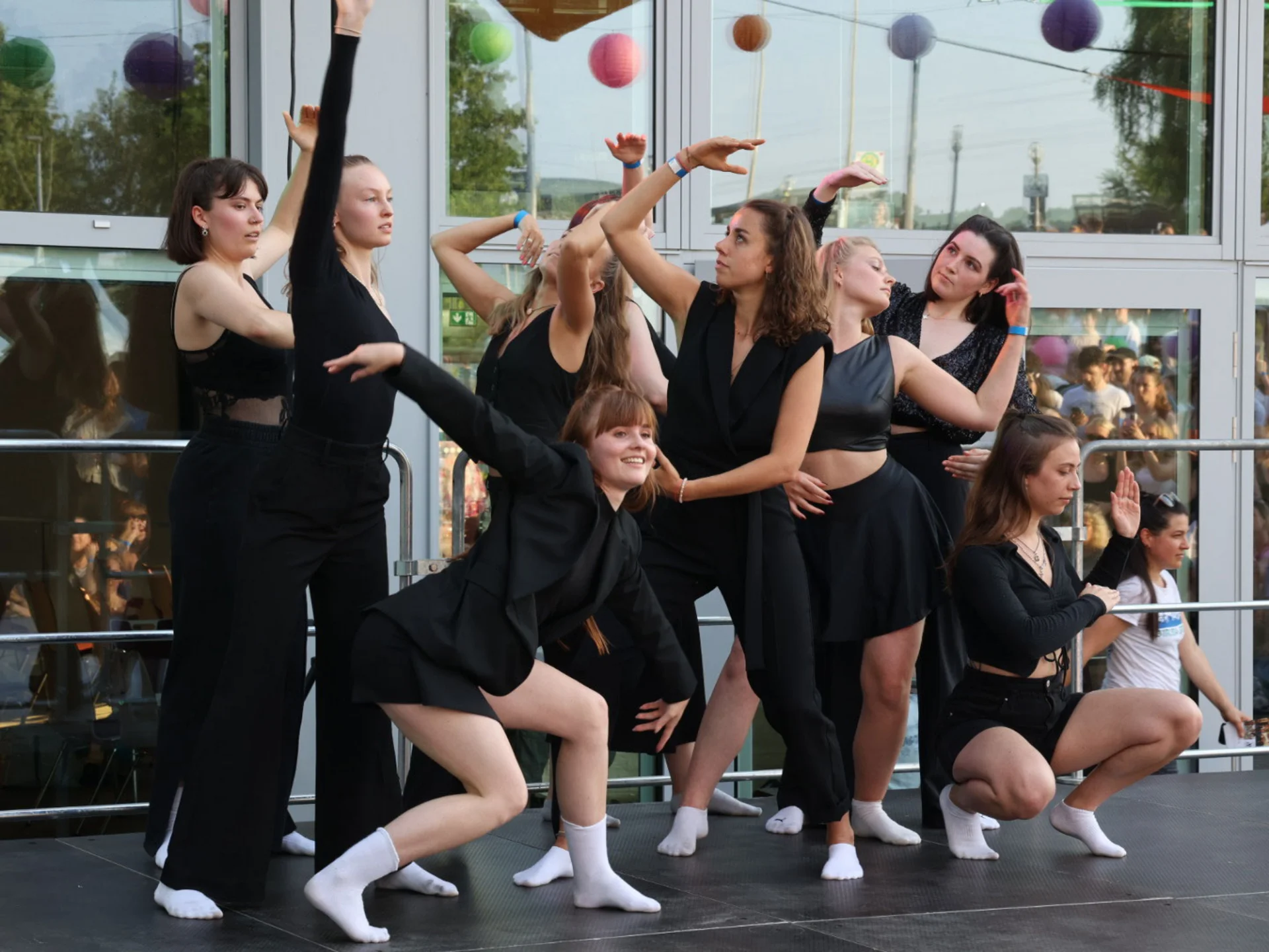 Foto einer Tanzgruppe. Die Tänzerinnen tragen alle schwarze Kleidung.