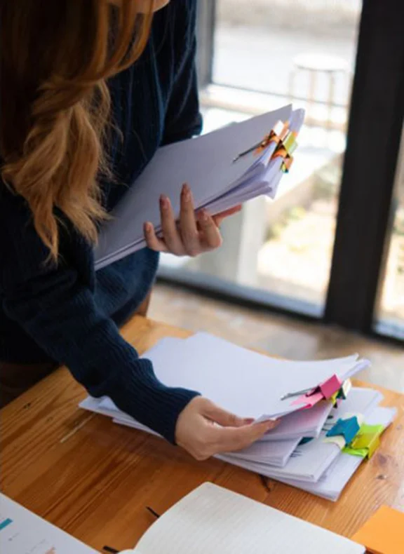 Eine Frau blättert dich einen Stapel Akten.