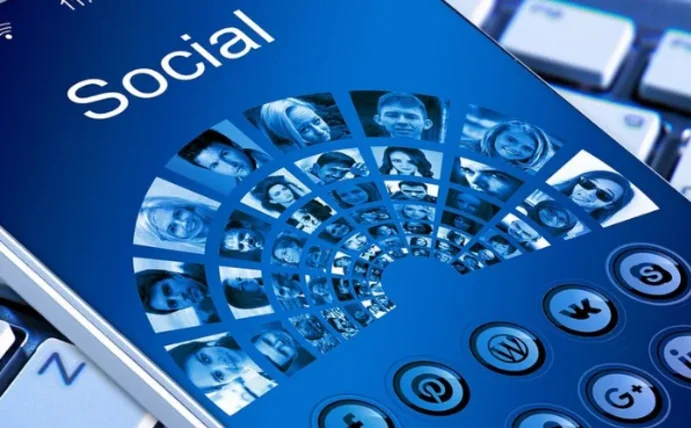Auf dem Bildschirm eines Smartphones steht "Social", darunter sind Porträts von Menschen in einem Halbkreis abgebildet, ebenso wie Icons von Social-Media-Plattformen.