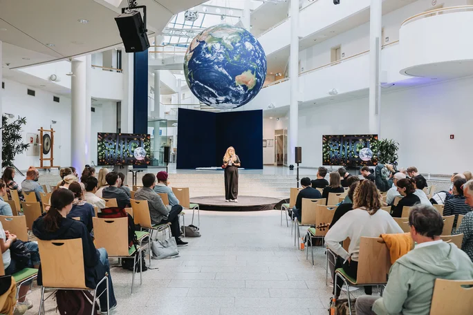 SWITCH conference for planetary education at the UW/H. (Photo: UW/H | Michael Schwettmann) Conference participants sit in the main hall of the UW/H and look towards the speaker in the centre of the hall. A large globe hangs from the ceiling.