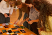 Students are bent over a table on which several photos and notes are spread out.