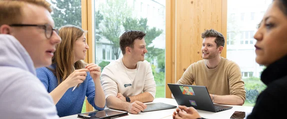 Fünf Studierende sitzen um einen Tisch