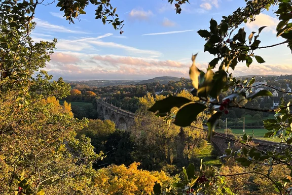 View of the Ruhr Viaduct in Witten (Photo: UW/H) In the foreground are the leaves and branches of a tree; in the background lies the Ruhr Valley with a stone viaduct.