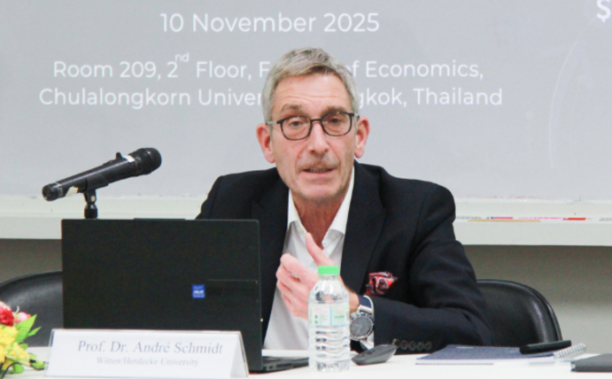 Prof Dr André Schmidt talks about global economic issues in Bangkok. (Photo: Chulalongkorn University) Prof Dr André Schmidt sits at a table in front of a microphone.