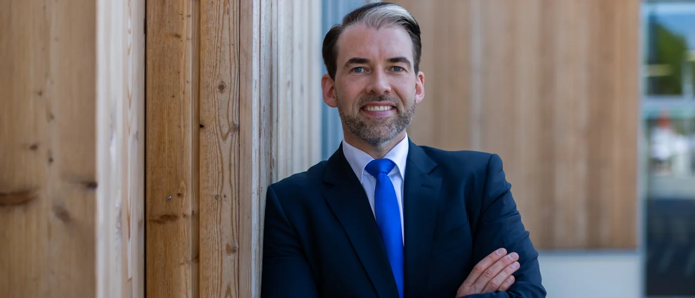 Portrait eines Mannes vor einer Holzfasade 