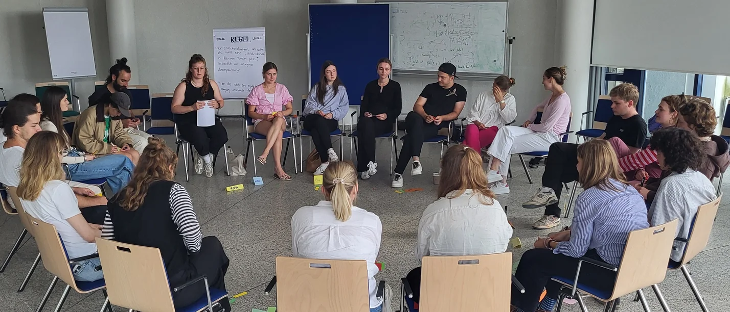 In the workshop, volunteers learn how to successfully organise projects as a team. (Photo: UW/H) A circle of chairs with several workshop participants in a bright room.
