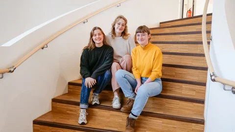 Team des Initiativlabors (Foto: UW/H) Ein Gruppenbild von drei Frauen, die auf einer Holztreppe sitzen.