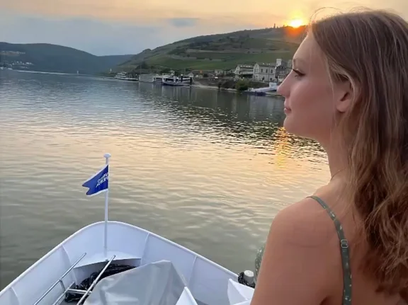 Für Pia Klee bedeutet der Neustart in Witten vor allem Unabhängigkeit. (Foto: privat) Pia Klee steht am Bug eines Schiffes und schaut über einen Fluss in den Sonnenuntergang.
