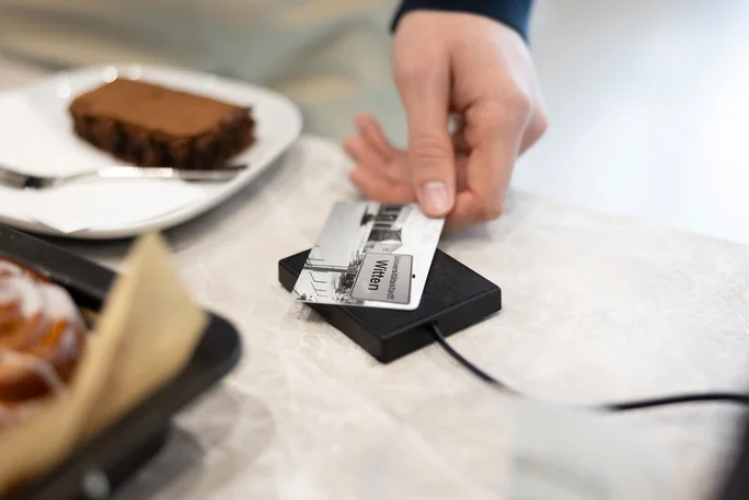 Ein Studierender bezahlt mit seiner Smart Card im Café Larix ein Stück Kuchen