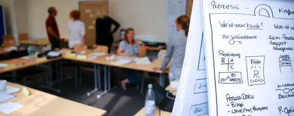 UW/H offers numerous benefits, including a comprehensive continuing education programme. (Photo: UW/H) Flipchart with graphics in the foreground, five people talking in the background.