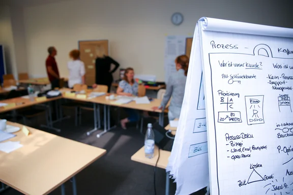 UW/H offers numerous benefits, including a comprehensive continuing education programme. (Photo: UW/H) Flipchart with graphics in the foreground, five people talking in the background.