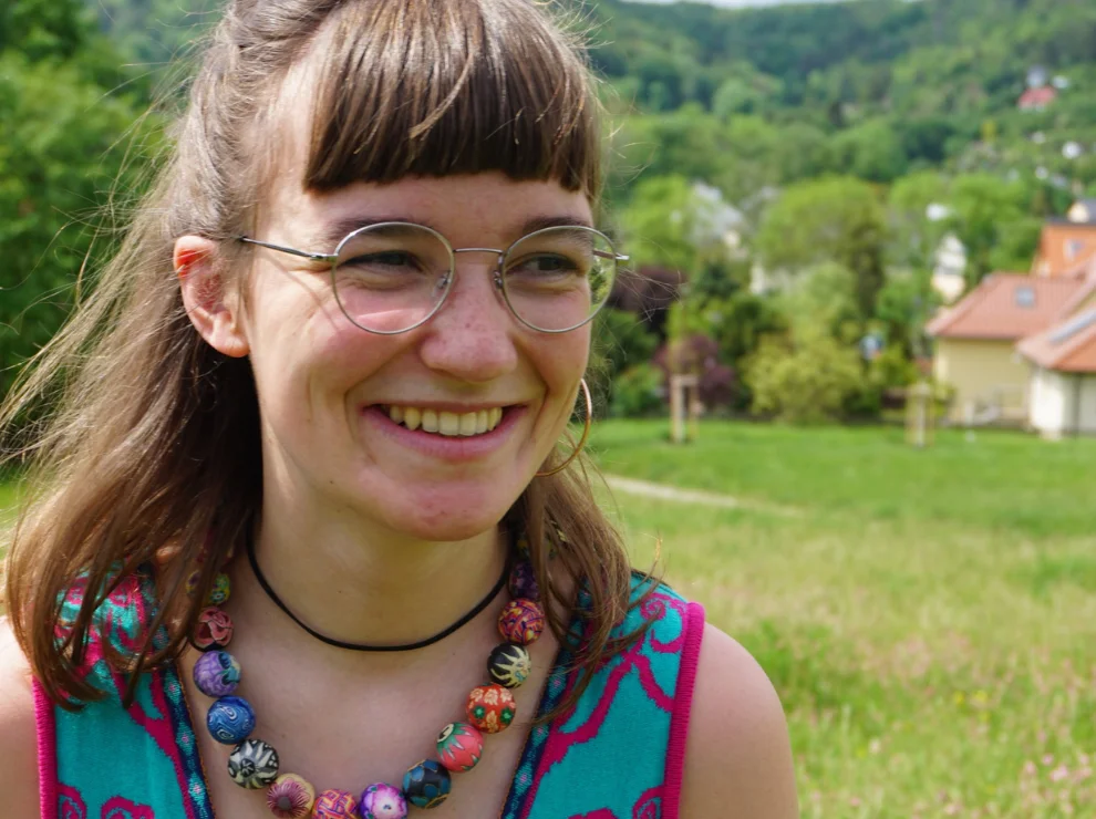 Foto von Emmi Mentzel. Im Hintergrund sind eine grüne Wiese und Bäume.