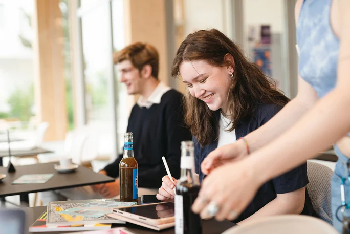 Studierende sitzen in der Mittagszeit im Café Larix.