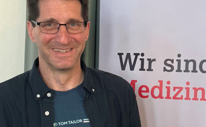 A man with a certificate in his hand smiles at the camera.