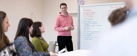 Human medicine students discuss a case on the whiteboard