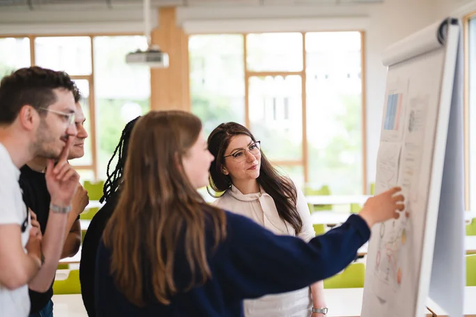 Seminar mit Studierenden im Bachelor of Choice an der UW/H (Foto: UW/H | Johannes Buldmann) Eine Gruppe Studierender steht am Flipchart und diskutiert ein Thema.