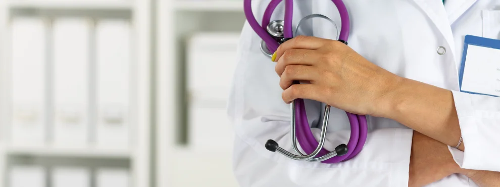 You can see a detail of a person in a smock holding a stethoscope.
