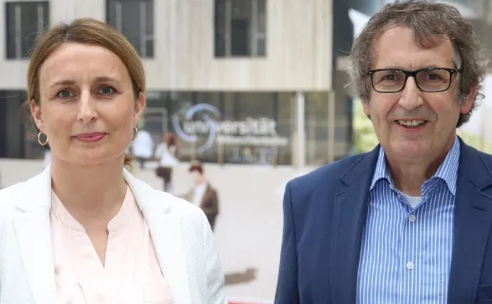 Eine Frau und ein Mann stehen nebeneinander und lächeln in die Kamera.