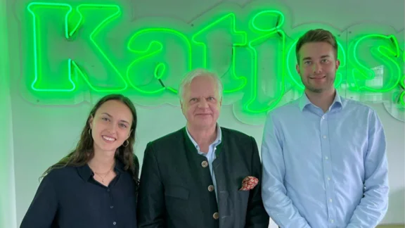 Drei Personen stehen vor einer Wand mit Katjes-Logo