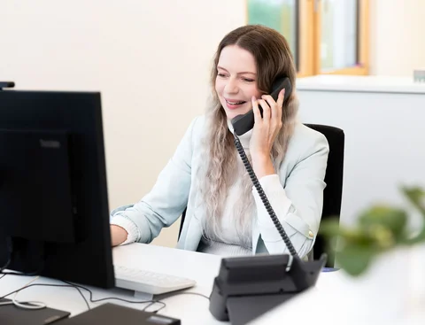 Die Studienberatung der Uni Witten/Herdecke ist gerne für dich da. EIne Frau sitzt vor einem Computer und telefoniert.