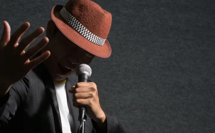 Man sieht einen Musiker, der ein Mikrofon in der Hand hält und singt.