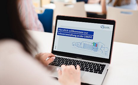 Screen eines Laptops, auf dem "Herzlich willkommen zur Infoveranstaltung an der UW/H" zu lesen ist 