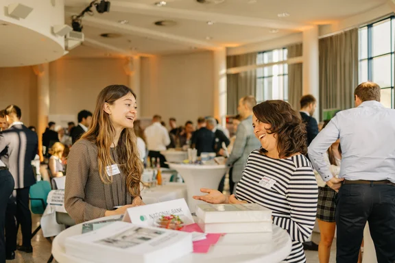 Students are making valuable contacts (Photo: UW/H | Michael Kotowski) A photo of two women standing at a bar table, chatting.