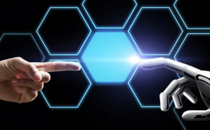 Symbolbild für die Zusammenarbeit von Mensch und KI. Man sieht eine menschliche Hand auf der linken Seite und eine Roboterhand auf der rechten Seite. Die Zeigefinger bewegen sich aufeinanderzu.