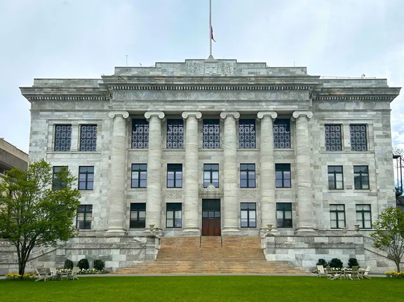 A front view of a historic building at Harvard Medical School, featuring a wide flight of steps, tall columns and a well-tended lawn in front of it.