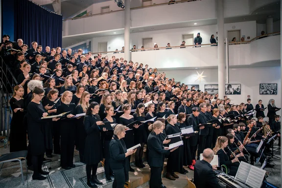 Foto eines Chors. Alle Sänger:innen sind schwarz gekleidet.
