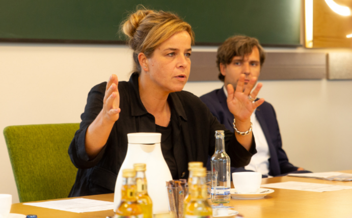 Mona Neubaur sitzt am Tisch und gestikuliert beim Sprechen mit den Händen.