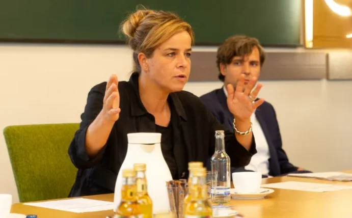 Mona Neubaur sitzt am Tisch und gestikuliert beim Sprechen mit den Händen.