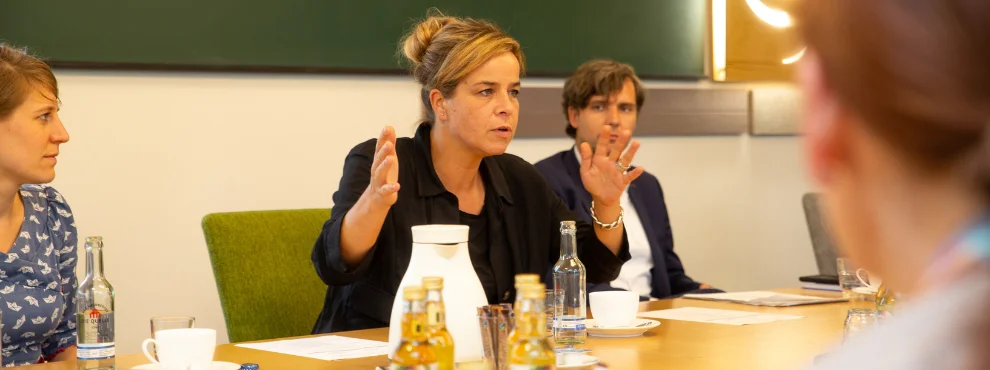 Mona Neubaur sitzt am Tisch und gestikuliert beim Sprechen mit den Händen.