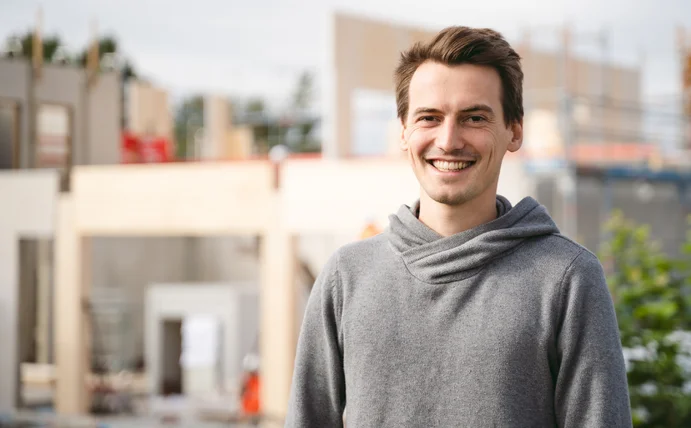 Dominik Treß in front of the construction site of the timber building